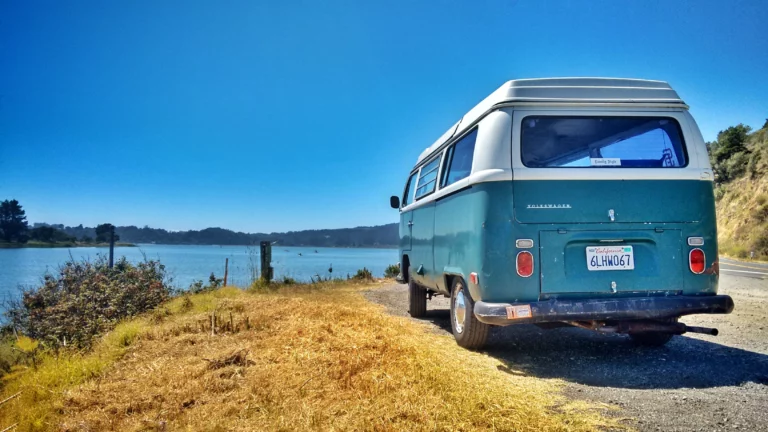 Blue and white campervan parked up overlooking a lake in the sunshine
