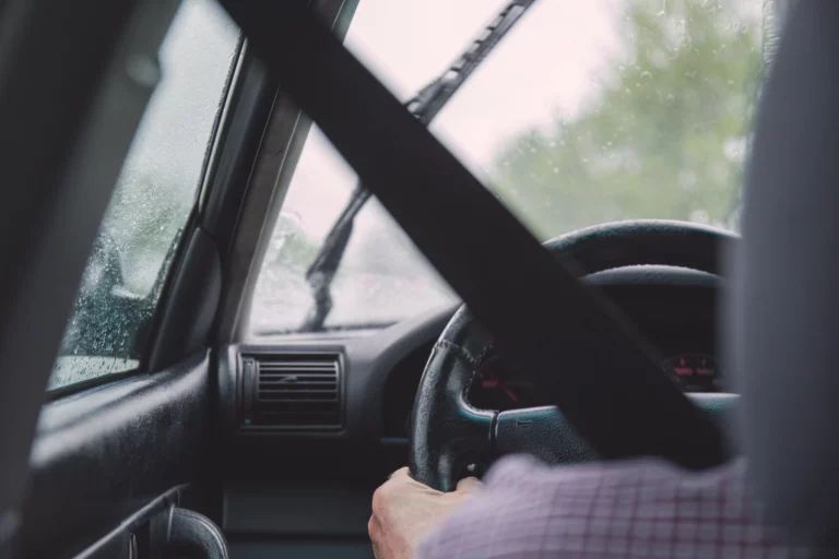 Driver sits behind steering wheel with seatbelt on