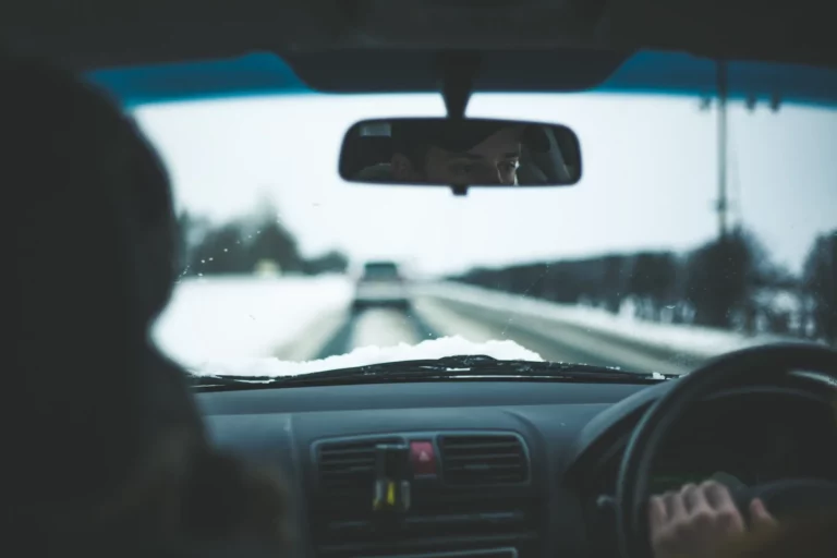 Man inside car near trees at daytime in snowy setting