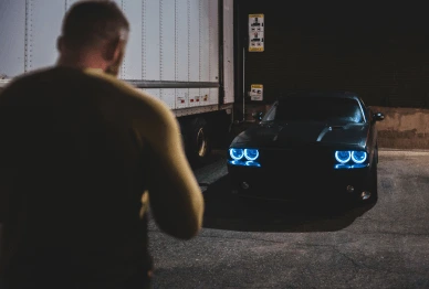 Man approaching parked car at night, illustrating vehicle theft prevention awareness.