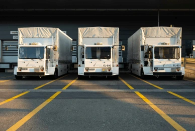 Three delivery trucks parked in a row at a loading dock, showcasing fleet compliance solutions for logistics.