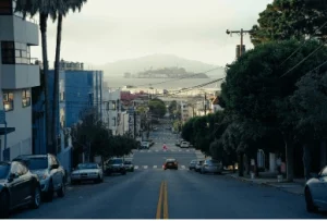 Urban street with parked cars, trees, and distant view of water, emphasizing tips for preventing vehicle theft.